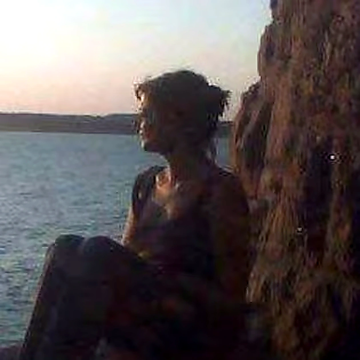 Kim Toner sitting on the rocks at sunset.