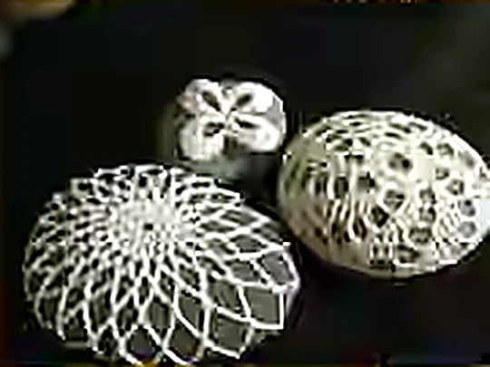 Three river stones wrapped in fine cream crochet, sitting on a dark ground.
